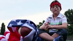Boy sitting next to American football ball with us national flag Stock Footage