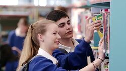 Boy and girl checking books and smiling in school library Stock Footage