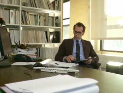 Medium shot. Dolly to the right around man on the phone and working on iPad. Camera positioned at corner of desk. Stock Footage