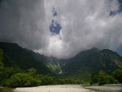 T/L clouds passing over green valley with river in foreground, Kamikochi, Japan Stock Footage