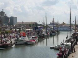 WS HA View of boats on old harbor and one ferry passing away, North Sea, North Frisia / Busum, Schleswig Holstein, Germany Stock Footage