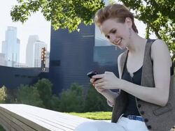 MS Young girl using cellular device outside in urban park smiling and having fun / Minneapolis, Minnesota, United States Stock Footage