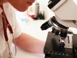 Female doctor places slide onto microscope Stock Footage