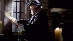 Candles burn on a table as Nostradamus reads a piece of parchment near a window. Stock Footage