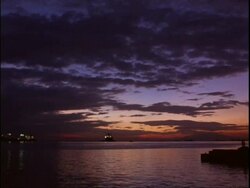 WA view across rippling water, Silhouetted fishing boat on horizon, colourful, atmospheric dusk sky, Manila bay, Philippines Stock Footage