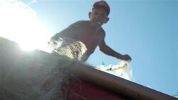 Brazilian fisherman untangles fishing net off the side of boat on Copacabana Beach Stock Footage