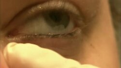 A medical professional with latex gloves pushes skin away from a patient's eye during an examination. Stock Footage