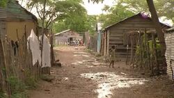 A little girl walks past shacks in a village. Stock Footage