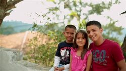 Hispanic teenage brother and younger siblings smile at camera (dolly-shot) Stock Footage