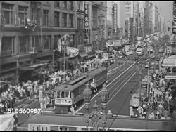 1948: LOS ANGELES, CALIFORNIA: HA WS Highway leading to city, Los Angeles BG. HA WS Downtown w/ crowded sidewalk & cable cars. WS Large corner city building. WS City intersection w/ people crossing street FG, Bank of America on opposite side. Instructional Video