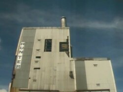  Sacrificial camera shot at base of mill building as it is demolished in a controlled implosion using explosives and falls toward the camera Stock Footage