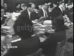 1941: IMMIGRATIONS: Two men entering Immigration & Naturalization building. Clerks at table going over paperwork, MS Woman holding fingerprint page. WS Immigrants in classroom singing. MS Teacher at map w/ immigrant women. Instructional Video