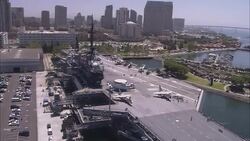Flags wave on the USS Midway CV-41 near the San Diego skyline. Stock Footage