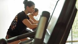 Women riding exercise bikes at gym Stock Footage