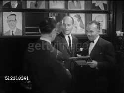 1952: TIME SQUARE: MANHATTAN, NEW YORK: NIGHT:  HA WS Time Square w/ buildings around, lit signs & advertisements, traffic moving on Broadway & 7th Avenue. INT VS Guests arriving & ordering at tables in Sardi's Restaurant. NYC, Theatre District Instructional Video