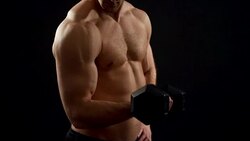 beautiful athlete trains with a dumbbell on a black background Stock Footage