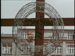 A wreath of barbed wire hangs on a cross on the Berlin Wall, Germany. News Clip