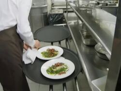 POV waiter taking prepared plates from the plating area in a restaurant kitchen to carry them to the dining room; camera follows waiter Stock Footage