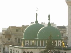 Tilt down from bullet riddled mosque to tanks blocking street Stock Footage