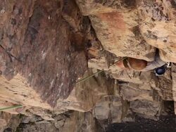 Handheld tilt of a rock-climber struggling up a cliff. Stock Footage