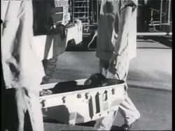 Scientists carry a chimpanzee strapped in a space capsule to a truck. News Clip