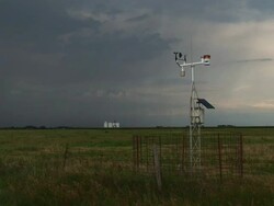 WS View of automated weather observation station with wind vane and anemometer in field and storm beyond / Kansas, United States Stock Footage