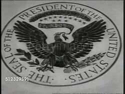 1917: WILSON: President Woodrow Wilson sitting in chair, nods slightly as if listening. CU Presidential Seal. President Woodrow Wilson sitting at desk, dipping pen into ink well, marking paper on desk, writing in center, not like signing, possibly Instructional Video