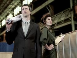 Businessman and businesswoman in warehouse with blueprint and clipboard Stock Footage