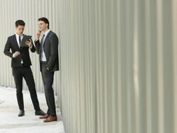 WS Two businessmen working on digital divices in front of a wall.  Stock Footage