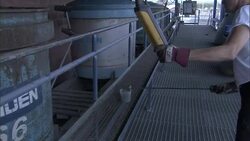 A worker takes a sample from a lidded tank as part of the mining process. Stock Footage