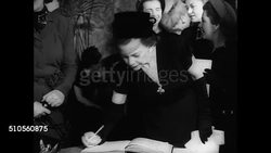 1947: N.Y. DRESS INSTITUTE PRESS WEEK: CU Invitation. INT VS Fashion editors signing in designer Eleanor Lambert (1903-2003) receiving guests. INT VS Editors typing looking at publicity pictures public relations going through photographs from file. Instructional Video
