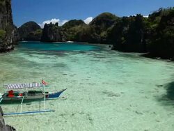 "WS outrigger boat anchored in idyllic tropical inlet surrounded by plants and sharp limestone cliffs / Small Lagoon, Miniloc Island, Bacuit Archipelago, El Nido, Palawan, Philippines" Stock Footage