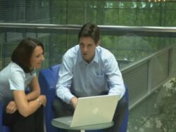 Man and woman in office looking at laptop, pan; UK Stock Footage