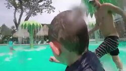 Father, son and daughter run in palm tree water park and son falls in water. Stock Footage