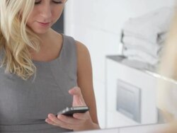 Female in bathroom receiving message on phone Stock Footage
