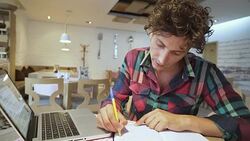 Man taking notes while looking at laptop screen. Stock Footage