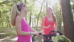 Young women talking and laughing while pushing jogging strollers in park Stock Footage