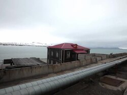 An old Russian house in Barentsburg, a Russian mining settlement on Svalbard archipelago with mountains covered by snow in the back Stock Footage