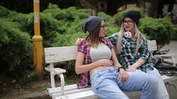 Careless girlfriends laughing at the park on the bench Stock Footage