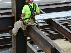 A steelworker sits on the edge of a support beam Stock Footage