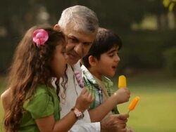 Senior man eating ice cream with his grandchildren in a park  Stock Footage
