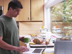 MS Man in kitchen, standing, holding and drinking coffee while using laptop / Portland, Oregon, United States Stock Footage