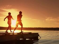 Young adult couple jumps into lake. Stock Footage