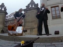Low angle medium shot muscians performing on the street / man putting money into hat / Prague Stock Footage