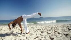 Capoeira martial artist cartwheels and lands impressive corkscrew on Brazilian beach in slow motion Stock Footage