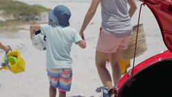 Family removing toys from trunk of convertible at beach Stock Footage