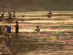 MS SLO MO Shot of people washing and bathing in small river in sunset light / Luang Prabang, Laos Stock Footage