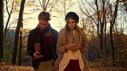 SLO MO Couple using mobile phones in autumn forest Stock Footage