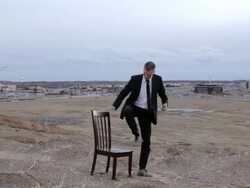 MS Young businessman dressed in black suit trying to get reception for his cell phone while sitting on  chair on top of  bluff in rural area / Maple Grove, Minnesota, United States Stock Footage