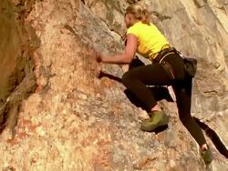 Low angle wide shot tilt up woman rock climbing on cliff / California Stock Footage